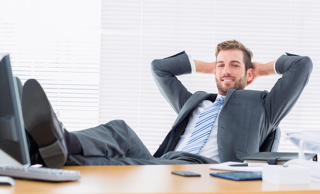 Homme d&#39;affaires confiant détendu assis avec les jambes sur le bureau