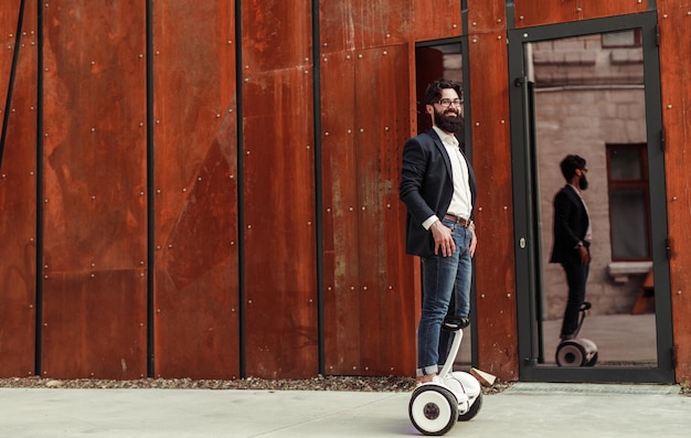 Homme d'affaires confiant sur gyroscooter contre le mur de la rue