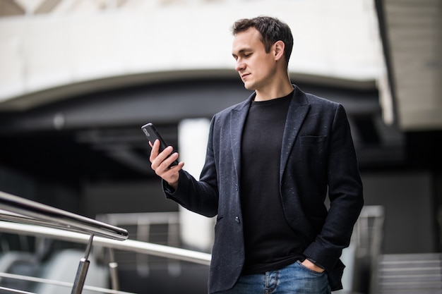 Homme d'affaires confiant. Joyeux jeune homme tenant un téléphone portable au bureau