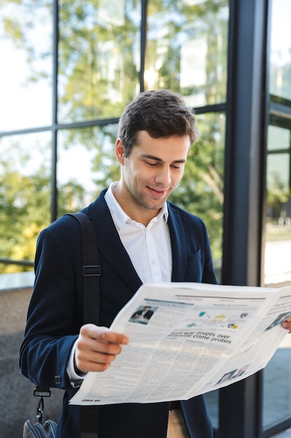 Homme d'affaires confiant, lisant le journal en se tenant debout à l'extérieur