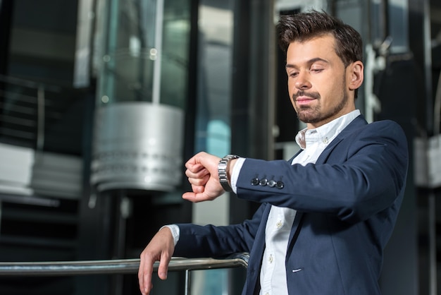 Homme d'affaires confiant regarde l'horloge.