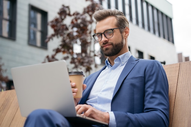 Homme d'affaires confiant utilisant un ordinateur portable travaillant en ligne assis sur le lieu de travail