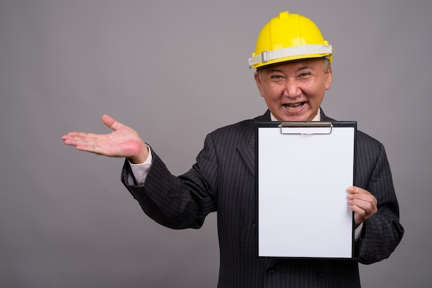 Photo homme d'affaires de construction asiatique mature contre mur gris