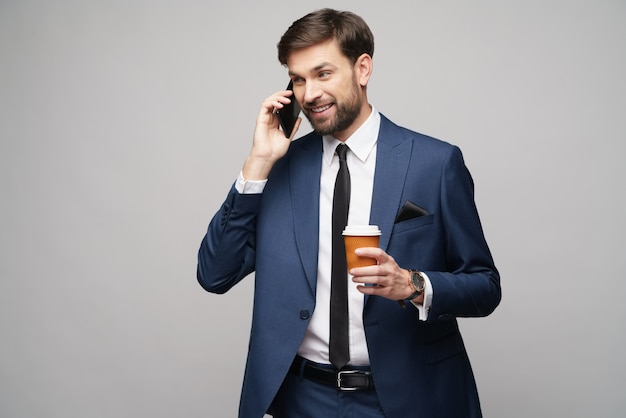 Homme affaires, conversation téléphone, et, tenue, tasse café, sur, mur gris