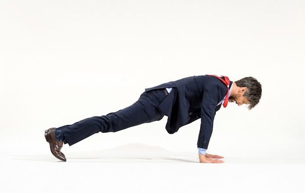 Homme d'affaires en costume élégant s'entrainant avec des pompes dans une vue latérale pleine longueur sur blanc dans un concept de remise en forme et de mode de vie sain et actif