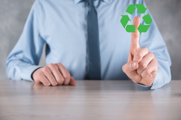 Homme d'affaires en costume sur fond sombre détient une icône de recyclage, signe dans ses mains. Concept d'écologie, d'environnement et de conservation. Lumière bleue rouge néon.