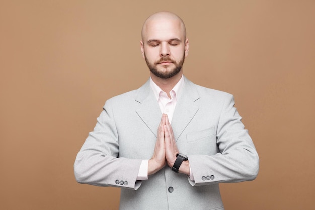 Homme d'affaires en costume gris clair classique debout avec une pose de yoga les bras levés et les yeux fermés