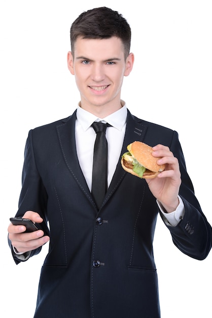 Homme d'affaires en costume mange hamburger.