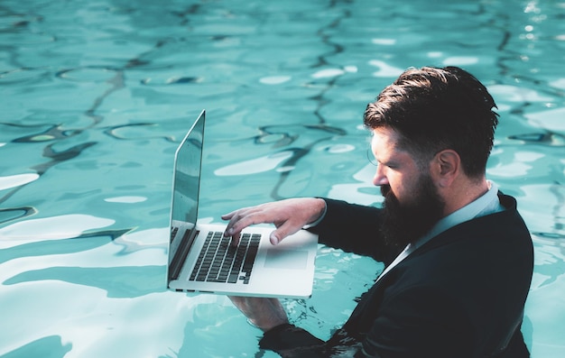 Homme d'affaires en costume avec ordinateur portable sur la piscine