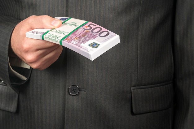 homme d'affaires en costume tenant un paquet d'argent d'une valeur nominale de cinq cents euros, gros plan