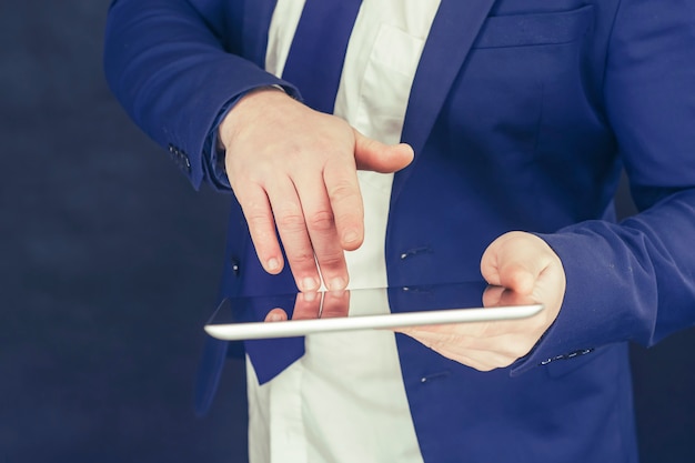 Homme d'affaires dans une chemise et une veste bleue avec tablette à la main.