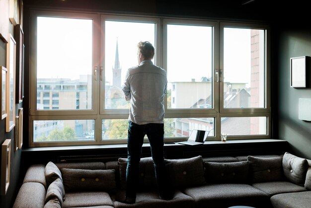 Homme d'affaires dans le salon d'un bureau regardant par la fenêtre