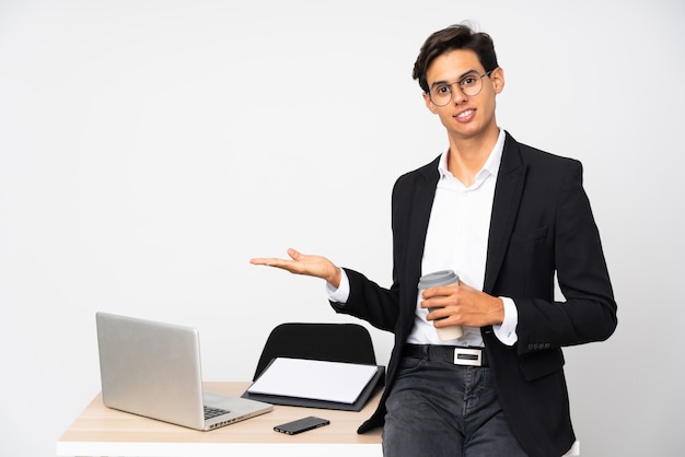 Homme d'affaires dans son bureau sur un mur isolé mur blanc étendant les mains sur le côté pour inviter à venir