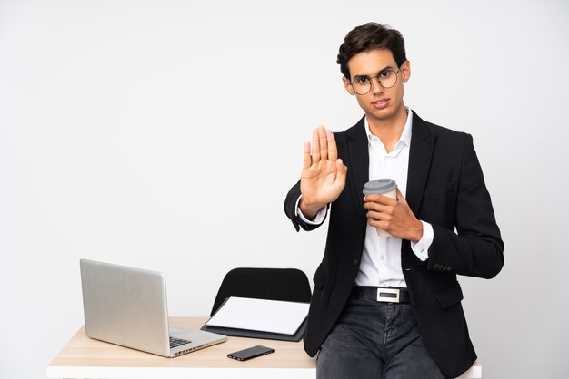 Homme d'affaires dans son bureau sur un mur isolé mur blanc faisant un geste d'arrêt avec sa main