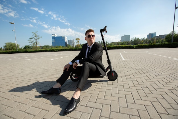 Homme d'affaires debout à côté d'un scooter électrique