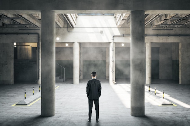 Homme d'affaires debout dans un parking souterrain intérieur