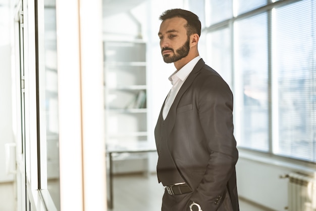 L'homme d'affaires debout près de la fenêtre du bureau