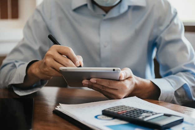 Homme d'affaires ou designer utilisant une tablette et un graphique sur le bureau dans un bureau moderne