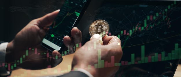 Homme d'affaires détenant des bitcoins dorés sur fond d'écran de graphique de trading informatique crypto-monnaie