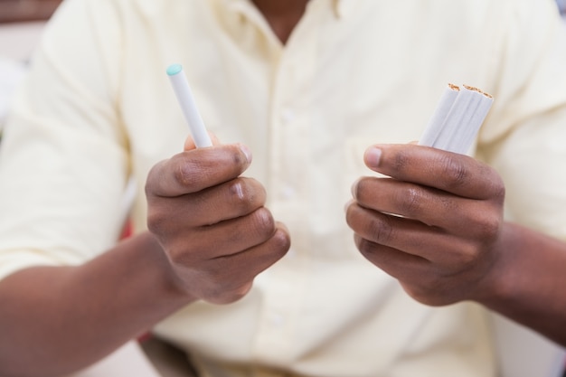 Homme d'affaires détenant des cigarettes électroniques et des cigarettes