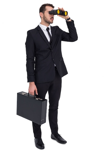 Homme d'affaires détenant une mallette tout en utilisant des jumelles