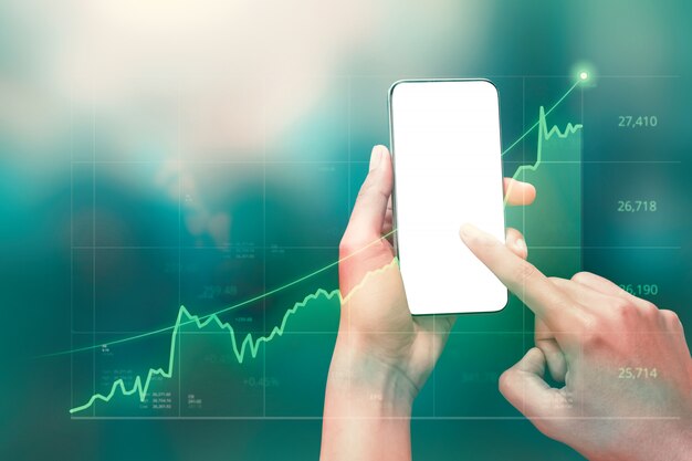 Homme d'affaires détenant un smartphone et affichant des graphiques holographiques et des statistiques boursières réalisant des bénéfices.