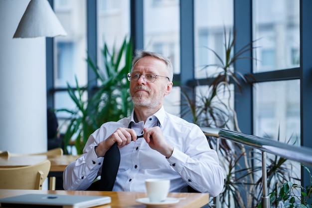 L'homme d'affaires directeur masculin adulte a travaillé avec succès et à la fin de la journée boit du café sans veste