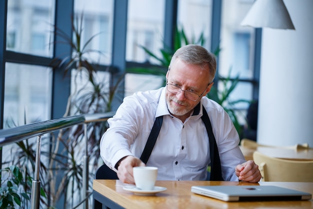 L'homme d'affaires directeur masculin adulte a travaillé avec succès et à la fin de la journée boit du café sans veste