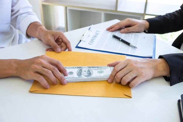 Homme d'affaires donnant des pots-de-vin dans l'enveloppe de leur partenaire pour réussir le contrat de transaction