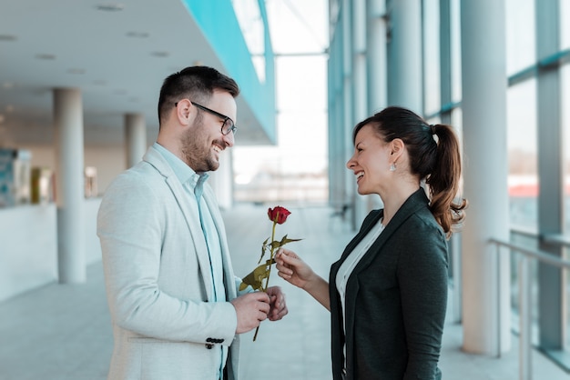 Homme d&#39;affaires donnant une rose à sa jolie collègue.