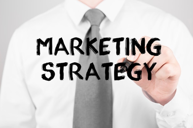 Homme d'affaires écrit la stratégie de marketing de mot avec le marqueur, concept d'entreprise