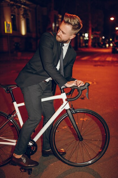Homme d'affaires élégant, faire du vélo dans la ville de nuit