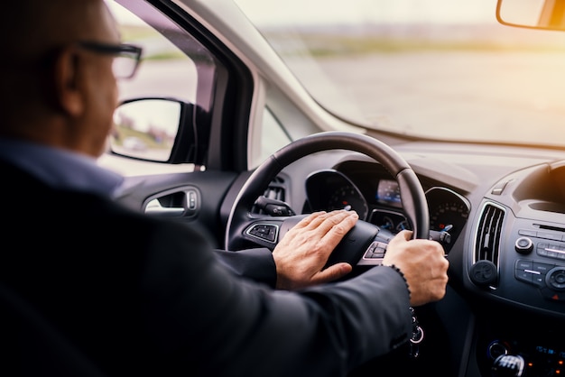 Homme d'affaires élégant professionnel mature en costume conduit une voiture et klaxonne.