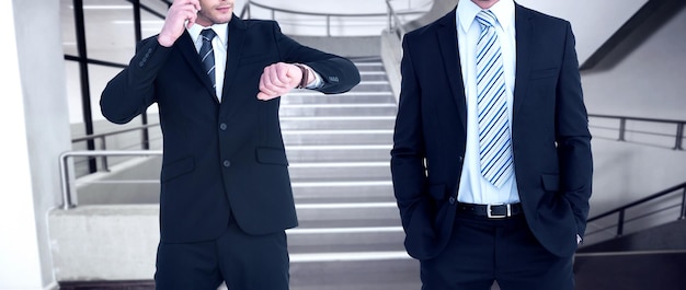 Homme d'affaires élégant souriant avec les mains dans les poches contre l'escalier vide