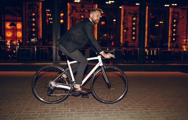 Homme d'affaires élégant à vélo dans la ville de nuit