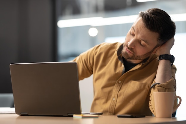 Homme d'affaires endormi travaillant sur un ordinateur portable assis au bureau au bureau