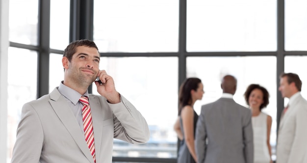 Homme d&#39;affaires enthousiaste au téléphone dans son bureau avec son équipe