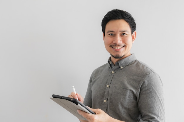 Homme d&#39;affaires entrepreneur heureux et sourire travaille sur sa tablette avec un fond gris.