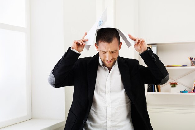 Photo homme d'affaires épuisé tenant des documents sur sa tête