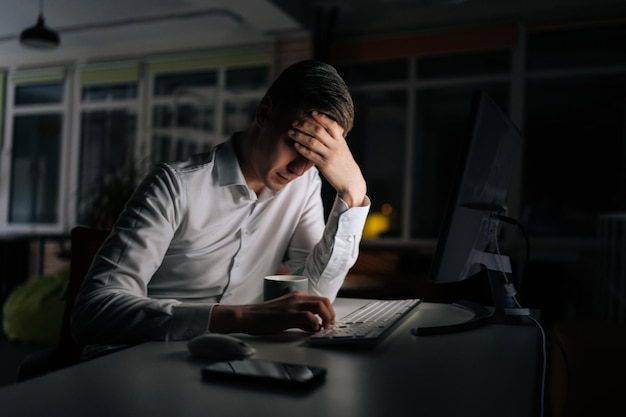 Photo un homme d'affaires épuisé travaillant seul au bureau le soir fatigué un directeur anxieux perdant un échec au travail