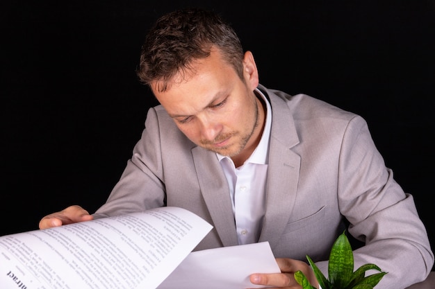 Homme d'affaires étudiant un document papier avec une expression sérieuse alors qu'il est assis à son bureau dans le bureau