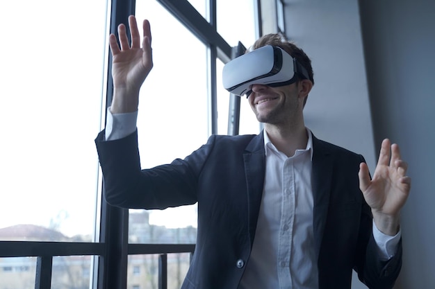 Homme d'affaires européen enthousiaste testant des lunettes vr au travail en utilisant la réalité virtuelle en entreprise