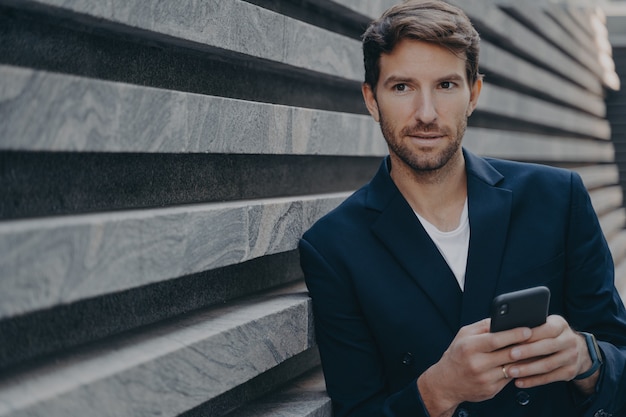 Un homme d'affaires examine attentivement les utilisations à distance du smartphone pense à la réussite future de sa carrière