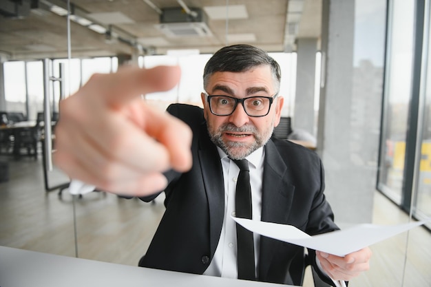 Homme d'affaires fâché s'asseyant à la table et criant au-dessus