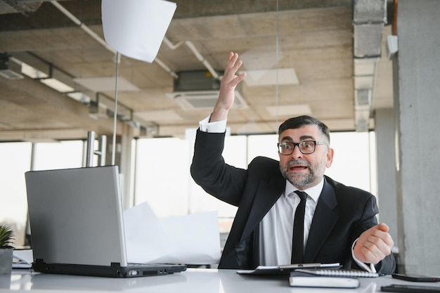 Homme d'affaires fâché s'asseyant à la table et criant au-dessus