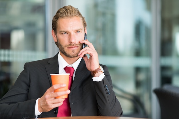 Homme d&#39;affaires faisant un appel téléphonique tout en buvant du café