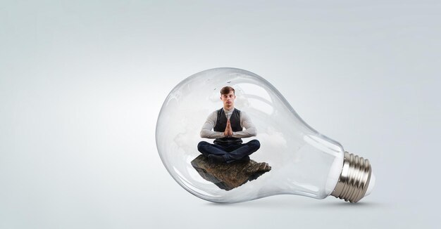 Homme d'affaires faisant du yoga dans la pose de lotus à l'intérieur de l'ampoule