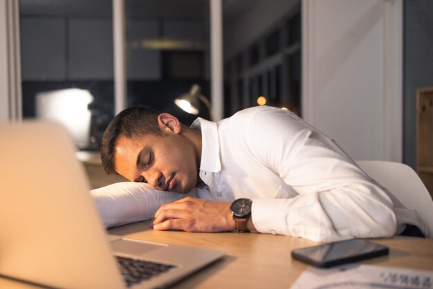 Homme d'affaires fatigué au travail et employé de bureau endormi se sentant épuisé par la date limite de nuit