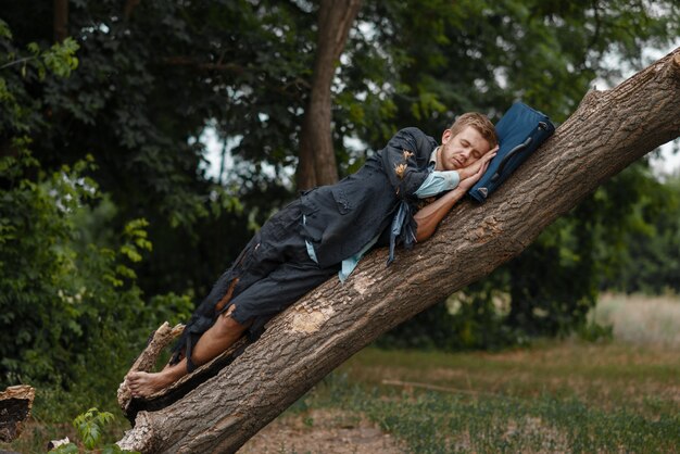 Homme d'affaires fatigué en costume déchiré dormant sur l'arbre sur l'île déserte. Concept de risque commercial, d'effondrement ou de faillite