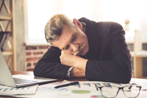 Homme d'affaires fatigué dans des vêtements classiques est la sieste sur la table.